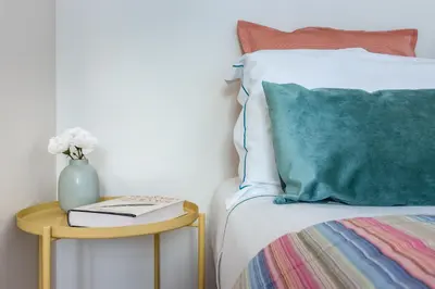 a bed with a vase on a side table with a book at Formosa Flats in Porto