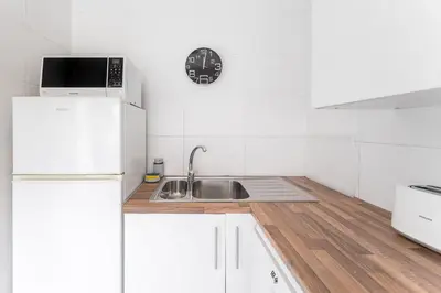 a white kitchen with a sink and a refrigerator at Casa Trindade in Porto