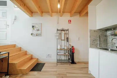 a staircase in a kitchen with white walls and wooden floors at Historic & Sunny Mezzanine Bolhão by Vacationy in Porto