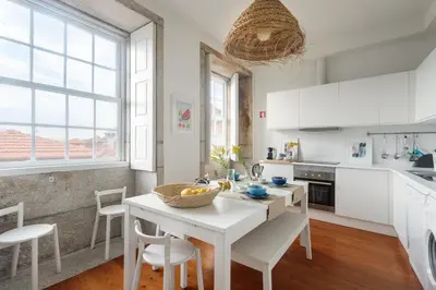 a kitchen with white cabinets and a table and chairs at Own Places Clérigos Apartments in Porto