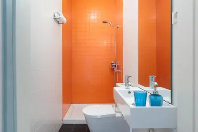 an orange bathroom with a toilet and a sink at Own Places Clérigos Apartments in Porto