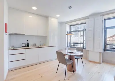 a kitchen with white cabinets and a table and chairs at Oporto Street Sá de Noronha in Porto