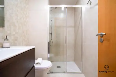 a bathroom with a shower with a toilet and a sink at Locally Yours São Bento Apartments in Porto