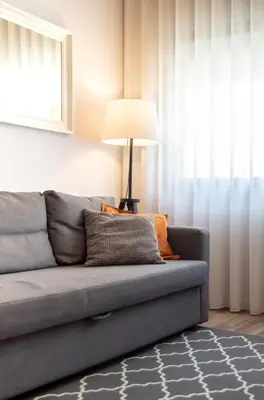a living room with a gray couch and a lamp at LL Picaria 16 in Porto