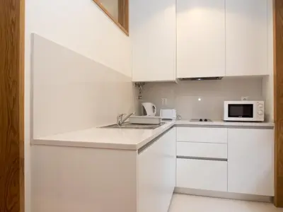 a white kitchen with white cabinets and a microwave at Belomont6 Apartments in Porto