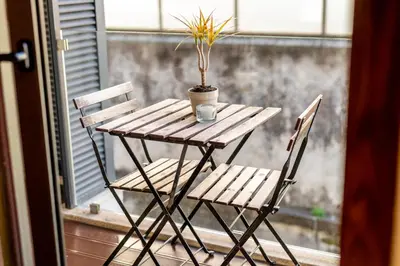 a wooden table with two chairs and a plant on a window at Merc Porto Santa Catarina in Porto