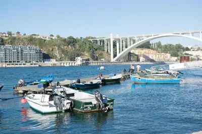 a group of boats docked in a river with a bridge at Merc Porto Santa Catarina in Porto