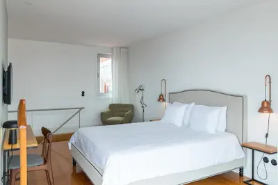 a bedroom with a white bed and a chair at GuestReady - Picaria Living Quarters in Porto
