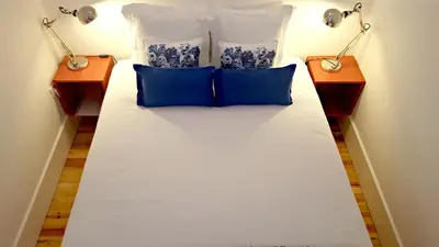 a bed with two blue pillows and two lamps at Flowers Center in Porto