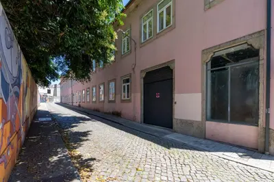an empty street with a pink building with a garage at Apartamento City Center in Porto