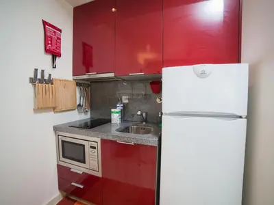 a kitchen with red cabinets and a white refrigerator at OPORTO GUEST - Cedofeita in Porto