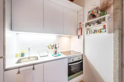 a kitchen with white cabinets and a sink and a refrigerator at Home in Porto - Cozy 2BR Duplex by LovelyStay in Porto