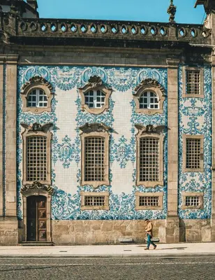 a woman walking past a building with blue and white tiles at Gardenia Urban Retreat in Porto