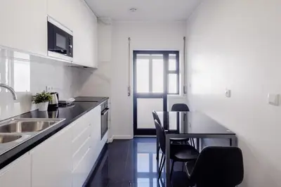 a kitchen with a sink and a table with chairs at Music House 3 bedroom Apt w garage in Porto