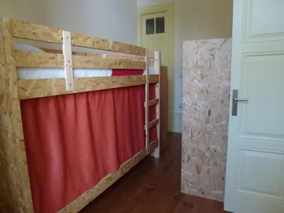a bedroom with a bunk bed and a red curtain at Canvas Atelier Hostel in Porto