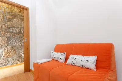 an orange couch with two pillows on it in a room at Goabio Apartment 3 Riverview in Porto
