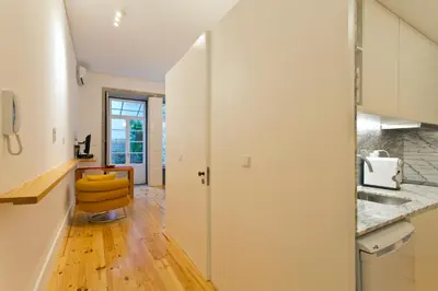 a kitchen with white cabinets and a yellow chair at 45 Flores: Rua das Flores/S.Bento in Porto