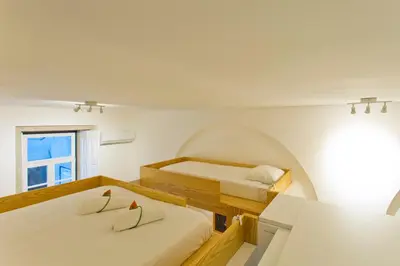 two beds in a room with a window at 45 Flores: Rua das Flores/S.Bento in Porto