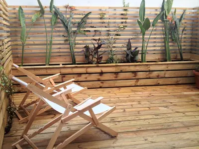 a wooden chair sitting on a deck with plants at 45 Flores: Rua das Flores/S.Bento in Porto