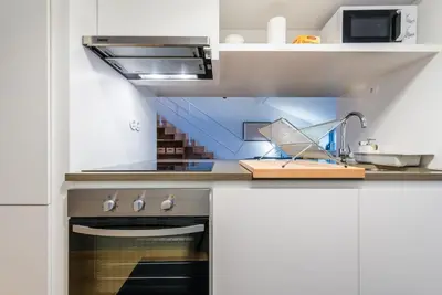 a kitchen with white cabinets and a stove top oven at GuestReady - Mezzanine at the Bridge in Porto