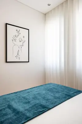 a bedroom with a turquoise rug and a picture on the wall at Casa das Musas in Porto