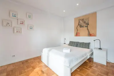a white bedroom with a white bed and a painting at GuestReady - Pratinhas in Porto