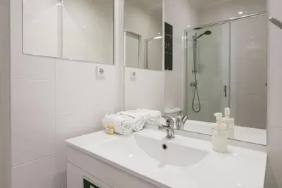 a white bathroom with a sink and a shower at GuestReady - Pratinhas in Porto