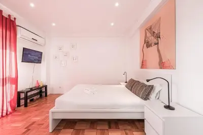 a white bedroom with a white bed and a red curtain at GuestReady - Pratinhas in Porto