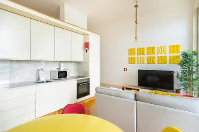 a kitchen with white cabinets and a table and a tv at GuestReady - Urban oasis with private balcony in Porto