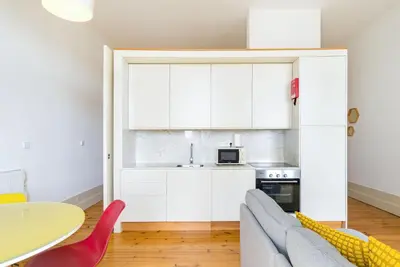 a kitchen with white cabinets and a couch and a table at GuestReady - Urban oasis with private balcony in Porto