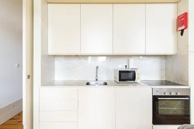 a white kitchen with a sink and a microwave at GuestReady - Urban oasis with private balcony in Porto