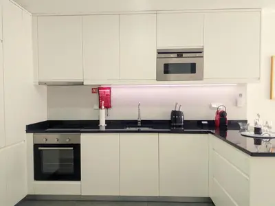 a white kitchen with white cabinets and a microwave at H2O Porto Ribeira in Porto