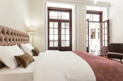 a bedroom with a large white bed and two windows at Chateau Belomonte in Porto
