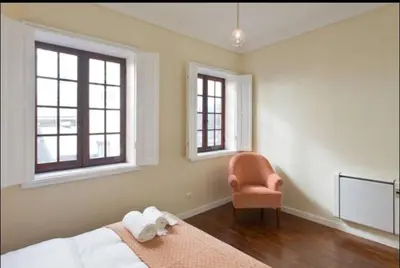 a bedroom with a bed and a chair and windows at Chateau Belomonte in Porto