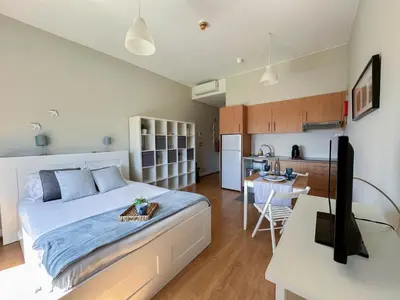 a bedroom with a large bed and a kitchen at Oporto Trindade Residence in Porto