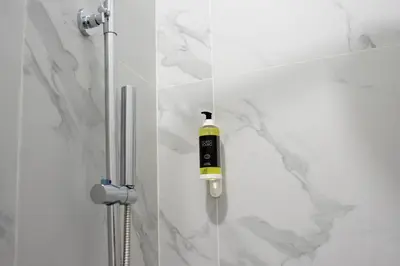 a shower with a black and yellow bottle on the wall at Oporto Trindade Residence in Porto
