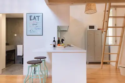 a kitchen with a white counter and two stools at Loft 72 in Porto