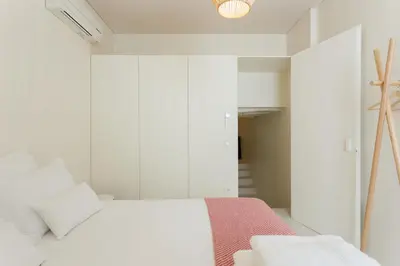 a bedroom with white walls and a white bed at Casa da Figueiroa in Porto