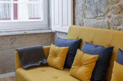 a yellow couch with several pillows on it at Old Stone Flats by Host Wise in Porto