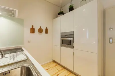 a kitchen with white cabinets and a sink at Old Stone Flats by Host Wise in Porto