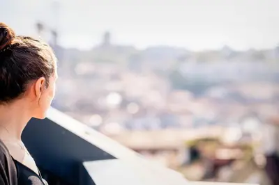 a woman looking out of a window at a city at Old Stone Flats by Host Wise in Porto