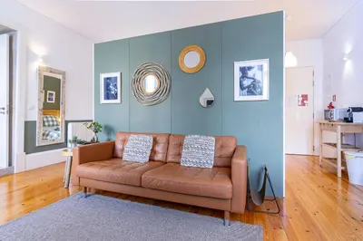 a living room with a brown couch and a blue wall at Cozy Studio Apartment in Porto