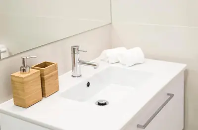 a white bathroom with a sink and a faucet at Bright Downtown Apartment in Porto