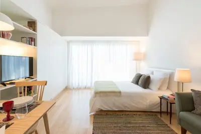 a bedroom with a bed and a couch and a tv at Bright Downtown Apartment in Porto