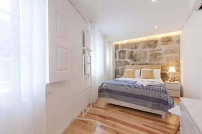 a bedroom with a bed and a stone wall at Sendme2Portugal: Loureiro in Porto