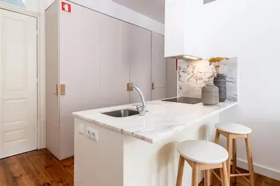 a white kitchen with a sink and two stools at Studio Sta in Porto