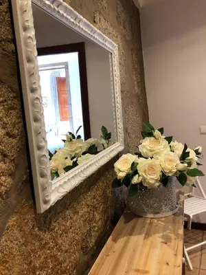 a vase of flowers on a table in front of a mirror at Turra Residence in Porto