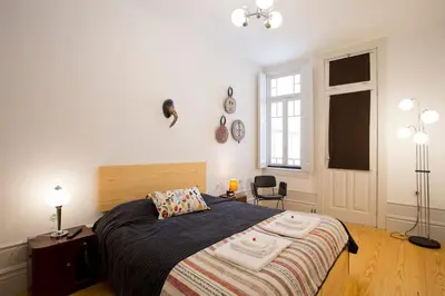 a bedroom with a bed and a chair and a window at 14º Esquadra — Cais das Pedras Guest House in Porto
