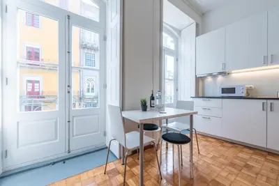 a kitchen with white cabinets and a table and chairs at GuestReady - Clérigos Virtudes Apartments in Porto