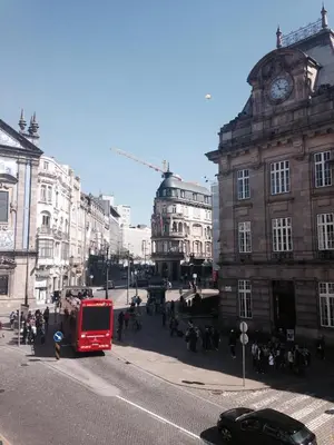 a red double decker bus driving down a city street at São Bento Front Homy Studio in Porto
